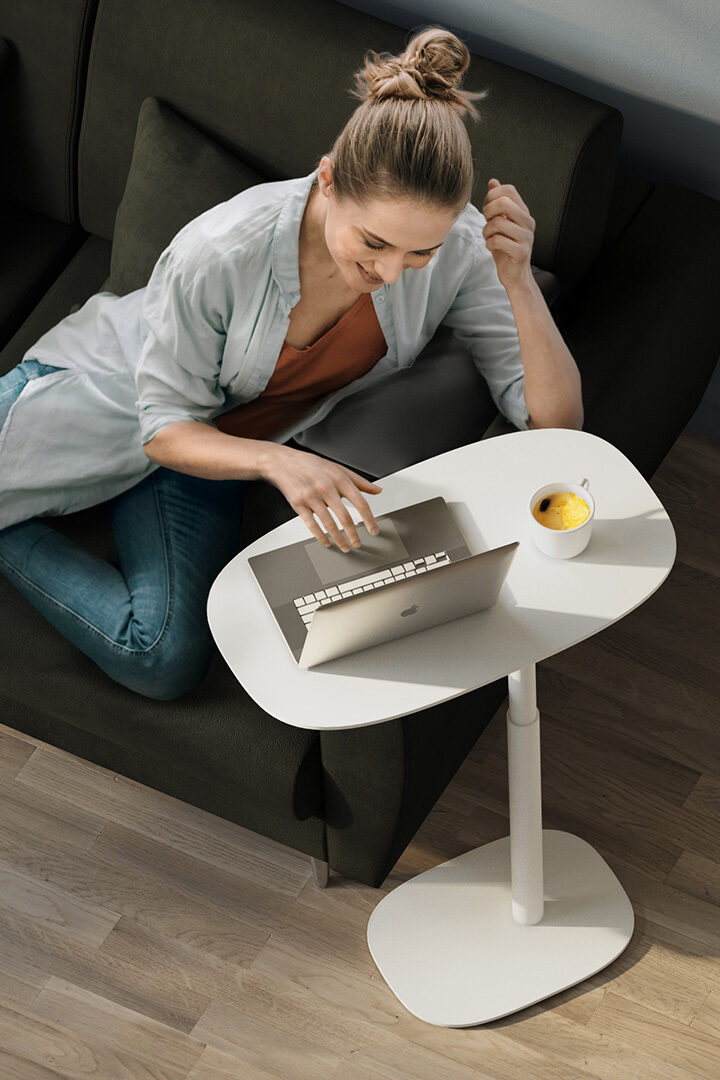 woman sitting using a white laptop table height adjustable BDI table